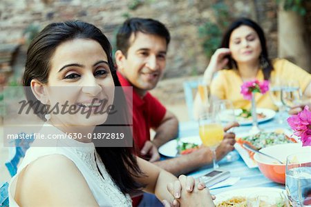 Mid femme adulte assis avec ses amis autour d'une table à manger