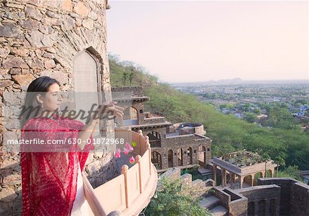Frau mit Blumen vom Balkon, Neemrana Fort Palace, Neemrana, Alwar, Rajasthan, Indien