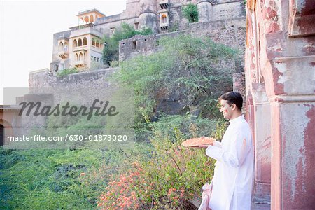 Man holding plate of powder paint at balcony of fort, Neemrana Fort Palace, Neemrana, Alwar, Rajasthan, India