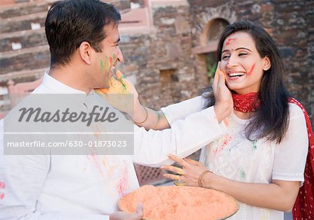 Close-up of a mid adult couple applying powder paint on each other's face