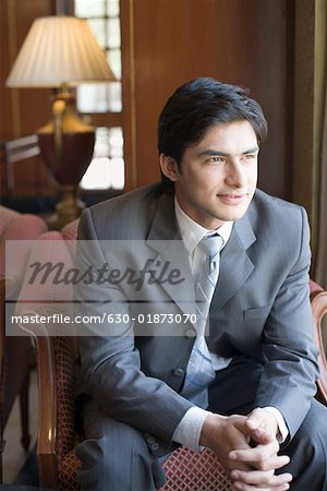 Businessman sitting in an armchair with his hands clasped and smiling