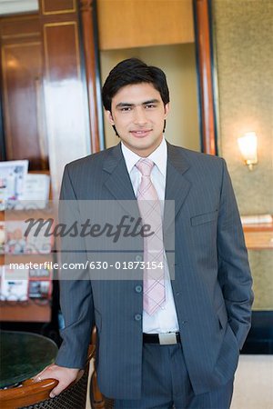 Portrait d'un homme d'affaires permanent avec sa main dans sa poche et souriant