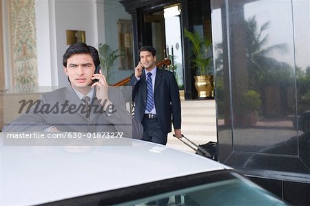 Businessman standing near a car and talking on a mobile phone