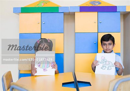 Portrait d'un écolier et une écolière montrant des peintures dans une salle de classe