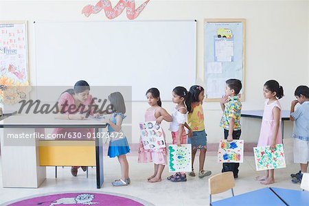 Teacher checking drawings of students in a classroom