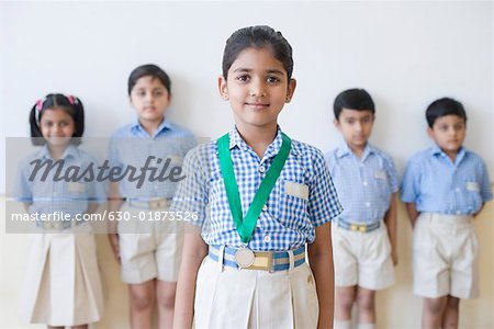 Portrait d'une écolière avec une médaille autour du cou avec ses camarades de classe en arrière-plan