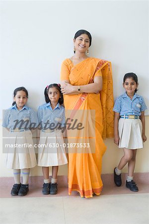 Portrait d'un enseignant permanent avec trois écolières et souriant