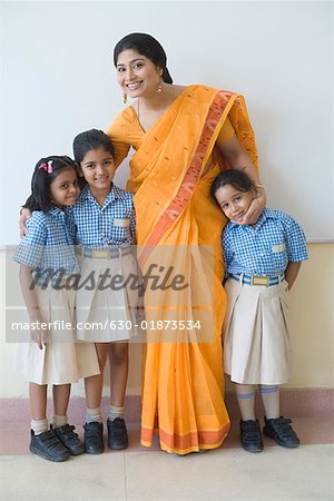 Portrait of a teacher standing with three students and smiling