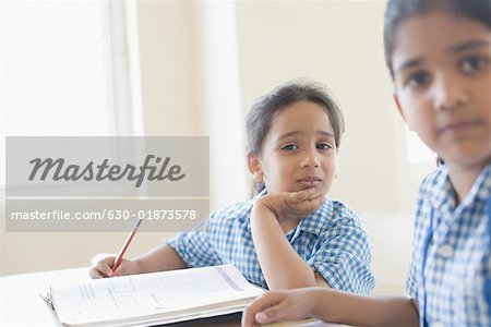 Écolières assis derrière un bureau avec sa main sur son menton