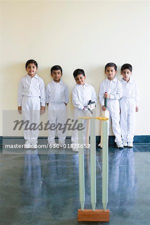 Portrait of five boys standing behind cricket stumps