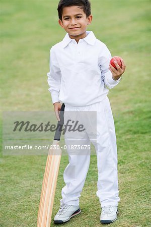 Boy holding a cricket bat and a cricket ball