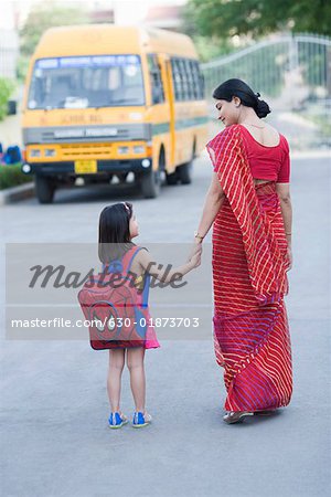 Rückansicht des eine Frau mittleren Alters die Hand ihrer Tochter hält und zu Fuß auf der Straße
