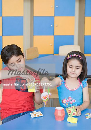 Two students making paper craft products in a classroom