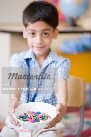 Portrait of a schoolboy holding candies in a bowl