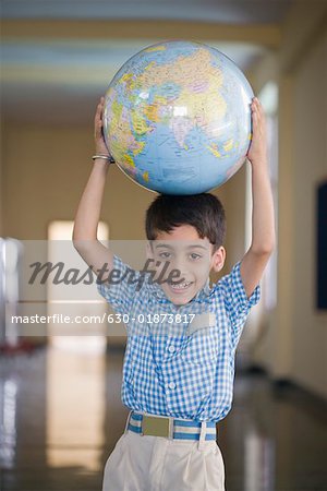 Portrait d'un écolier tenant un globe au-dessus de sa tête