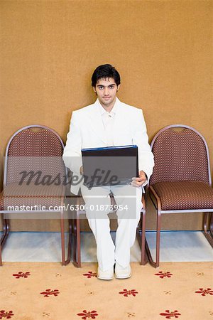 Portrait of a businessman sitting on a chair and using a laptop