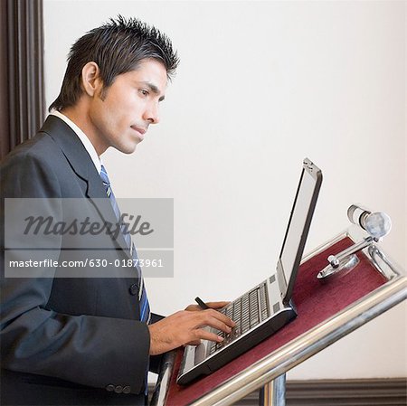 Side profile of a businessman using a laptop on a lectern