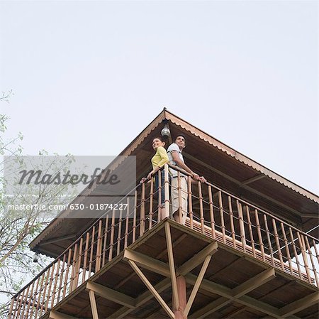 Low angle view of a young couple standing at the railing of a log cabin