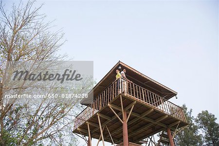 Low angle view of a young couple standing at the railing of a log cabin