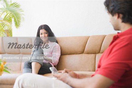 Young woman sitting on a couch and looking at a young man