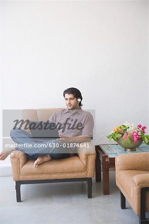 Young man sitting in an armchair and using a laptop