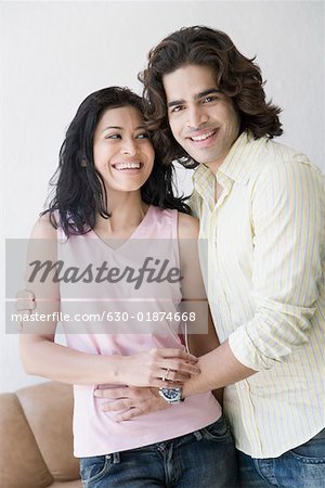 Portrait d'un jeune homme debout avec son bras autour d'une femme jeune et souriant