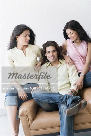 Young man sitting between two young women