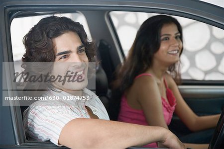 Side profile of a young couple sitting inside a car and smiling