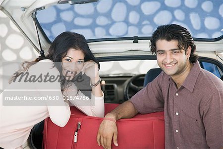 Jeune couple souriant ensemble dans le coffre d'une voiture