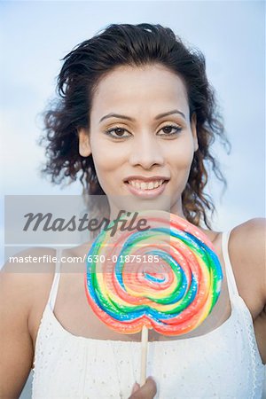 Portrait d'une jeune femme tenant un bonbon et souriant