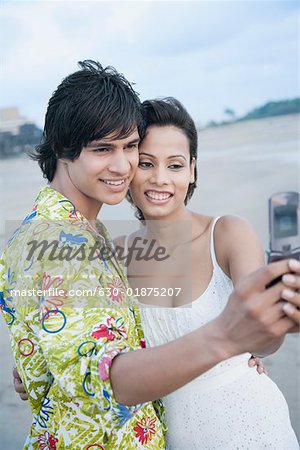 Side profile of a young couple taking a photograph of themselves with a mobile phone