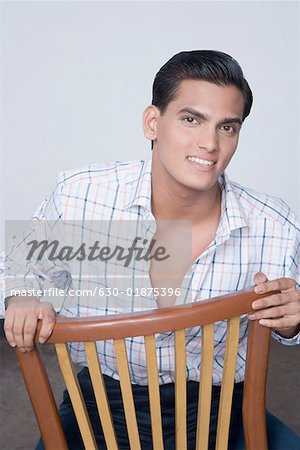 Portrait of a young man sitting on a chair and smiling