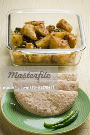 Close-up of chapattis in a plate with a bowl of potato sabzi