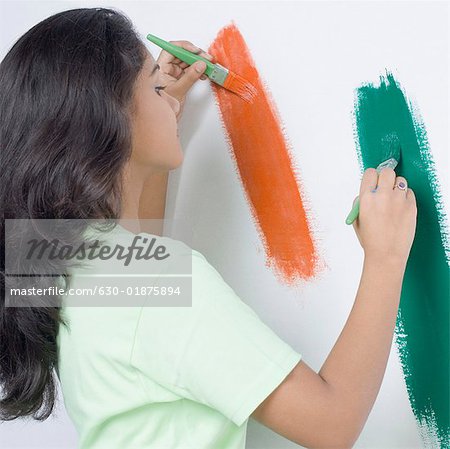 Seitenansicht einer jungen Frau, die indische Flagge auf eine Wand malen