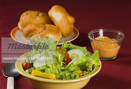 Close-up of a bowl of salad and a plate of buns