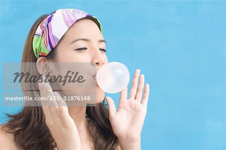 Gros plan d'une jeune femme soufflant de bubble-gum