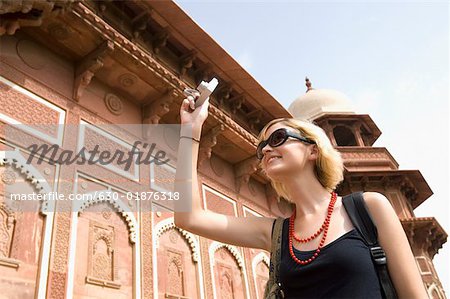 Vue d'angle faible d'une jeune femme de prendre une photo devant un mausolée, Taj Mahal, Agra, Uttar Pradesh, Inde