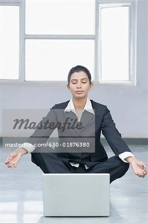 Femme d'affaires faisant du yoga en face d'un ordinateur portable
