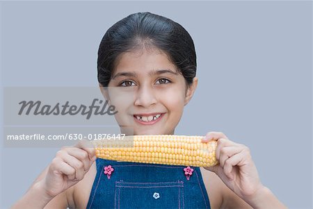 Portrait of a girl holding a corn cob and smiling