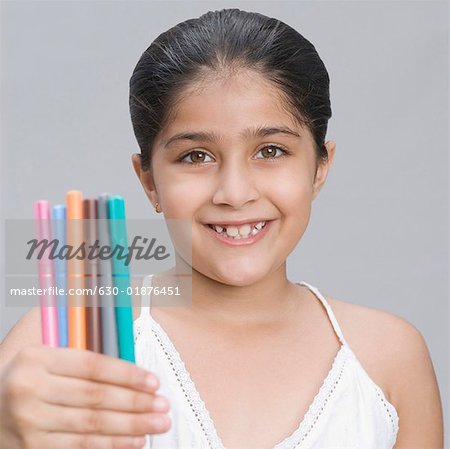 Portrait of a girl holding pens and smiling