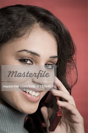 Portrait d'une jeune femme parlant sur un téléphone mobile et souriant