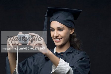 Gros plan d'un jeune diplômé de femme tenant un appareil photo numérique