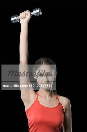 Portrait d'une jeune femme exerçant avec un haltère