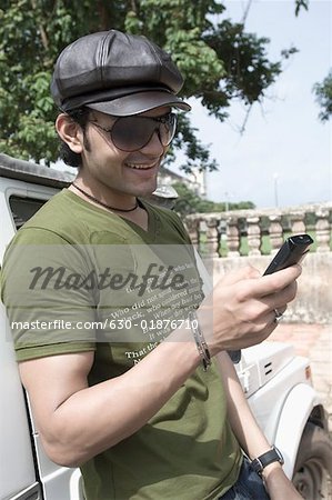 Nahaufnahme von einem jungen Mann Text messaging mit Handy und Lächeln, Goa, Indien