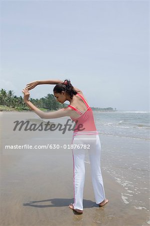 Rückansicht einer jungen Frau, die sich am Strand fit halten