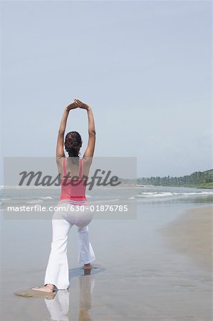 Rear view of a young woman exercising on the beach