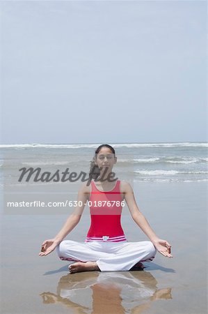 Junge Frau meditieren am Strand
