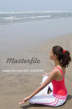 Profil de côté d'une jeune femme méditant sur la plage