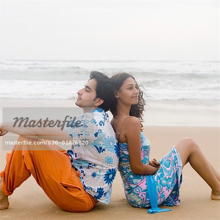 Side profile of a young couple sitting back to back