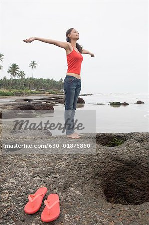 Young woman standing with her arms outstretched on the beach